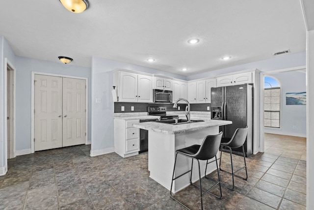 kitchen with a kitchen bar, white cabinetry, stainless steel appliances, an island with sink, and sink