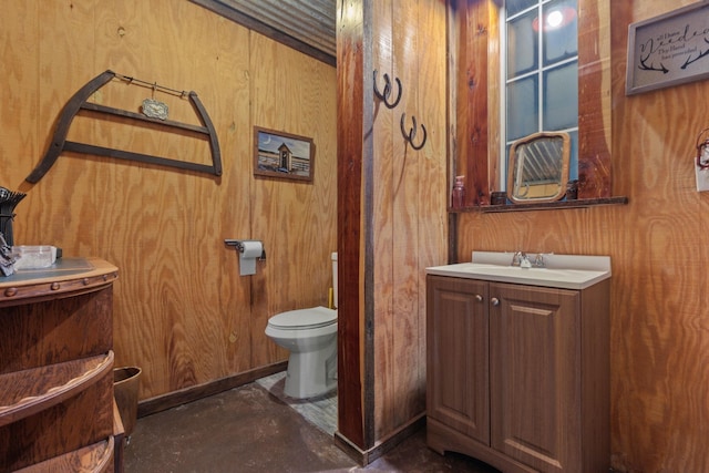 bathroom with toilet, vanity, concrete flooring, and wooden walls