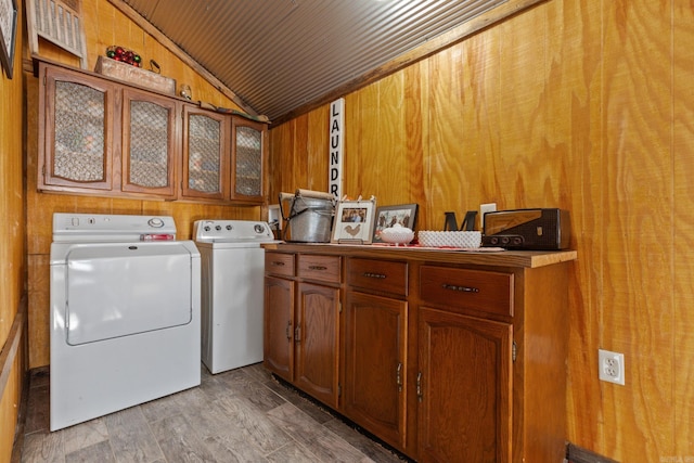 laundry area featuring cabinets, independent washer and dryer, and wood walls