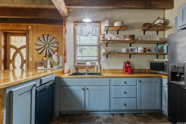 kitchen with sink, black appliances, butcher block counters, and wooden walls