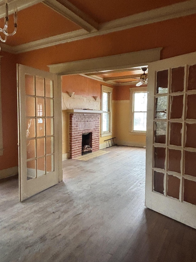 unfurnished living room featuring ceiling fan, a fireplace, and beamed ceiling