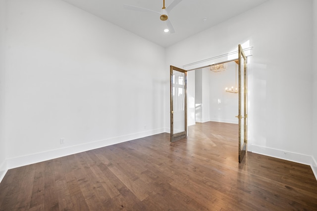 empty room featuring dark hardwood / wood-style flooring and ceiling fan with notable chandelier