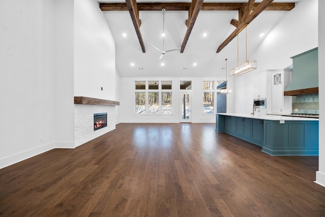 unfurnished living room with beam ceiling, dark hardwood / wood-style floors, and high vaulted ceiling