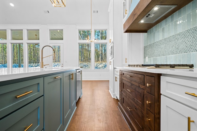 kitchen featuring sink, custom exhaust hood, white cabinetry, decorative light fixtures, and dark hardwood / wood-style flooring