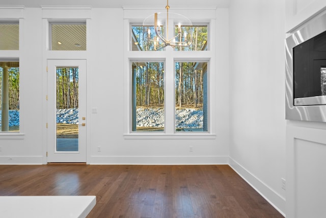 unfurnished dining area with dark hardwood / wood-style flooring, plenty of natural light, and a chandelier