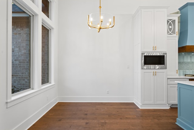 unfurnished dining area with an inviting chandelier and dark wood-type flooring