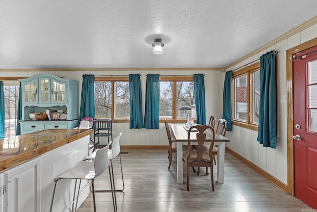 dining room with ornamental molding, a textured ceiling, and hardwood / wood-style flooring