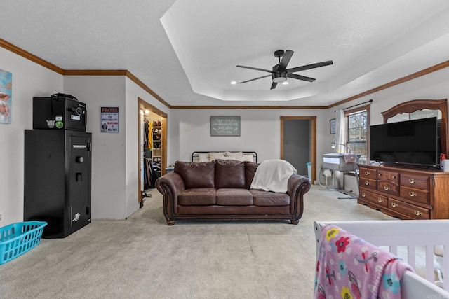 carpeted living room featuring ceiling fan, ornamental molding, and a raised ceiling