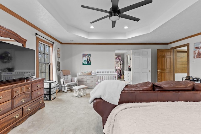 carpeted bedroom with ceiling fan, crown molding, and a tray ceiling