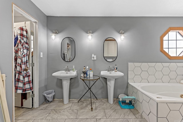 bathroom with tiled tub and double sink