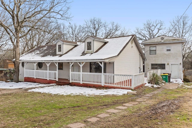 cape cod-style house featuring covered porch, a garage, and a yard