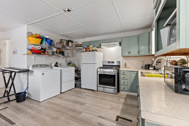 kitchen featuring washer and dryer, white refrigerator, light hardwood / wood-style floors, sink, and stainless steel range with gas stovetop