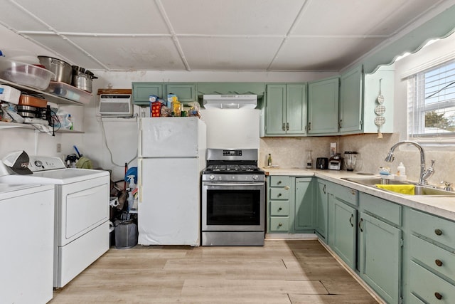 kitchen with white fridge, sink, stainless steel range with gas stovetop, light hardwood / wood-style flooring, and separate washer and dryer