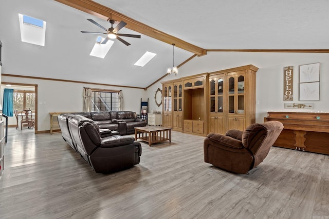 living room with ceiling fan with notable chandelier, vaulted ceiling with skylight, and hardwood / wood-style flooring