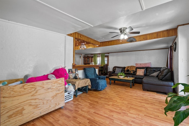 living room with ceiling fan, wood walls, and light hardwood / wood-style floors