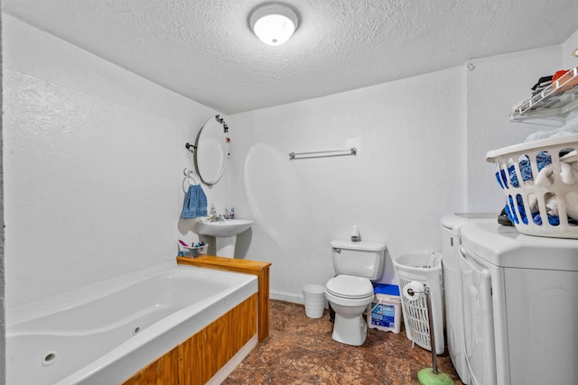 bathroom with toilet, sink, washer and clothes dryer, a textured ceiling, and a bathtub