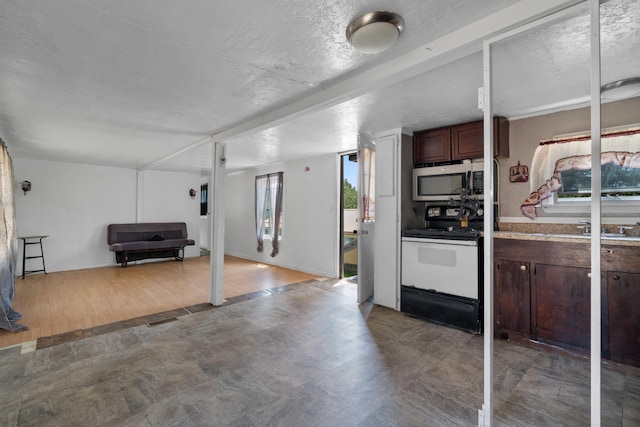 kitchen featuring sink, a textured ceiling, dark brown cabinets, and range with electric cooktop