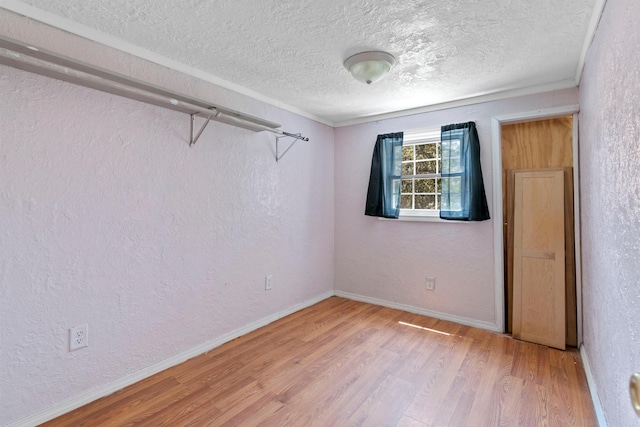 empty room with a textured ceiling, ornamental molding, and hardwood / wood-style floors