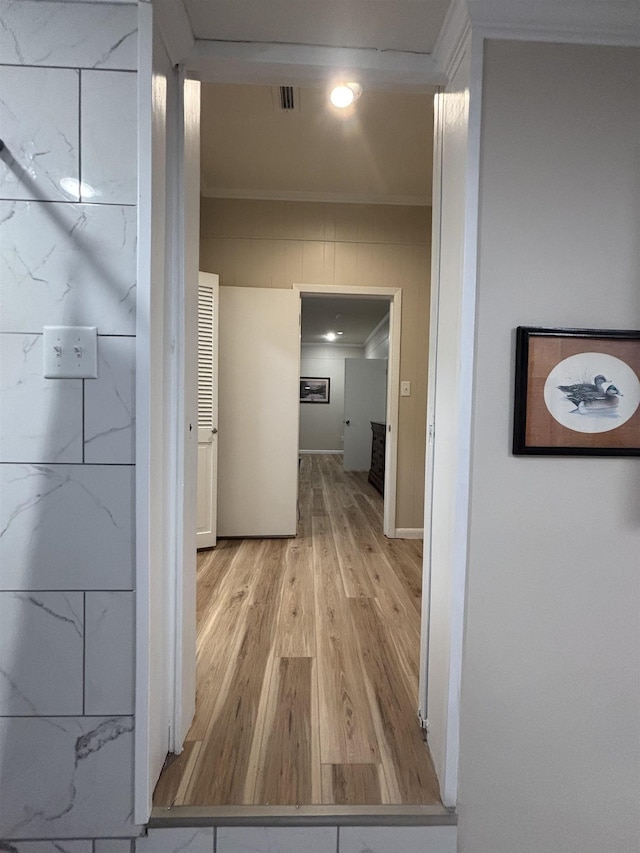 hallway with light hardwood / wood-style floors and ornamental molding