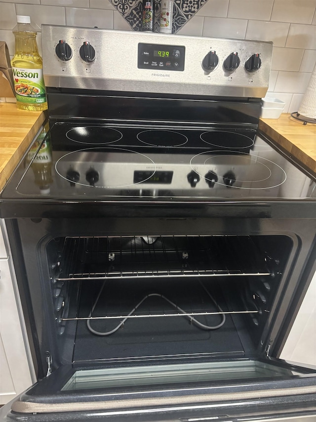 room details with tasteful backsplash, electric range, and wooden counters