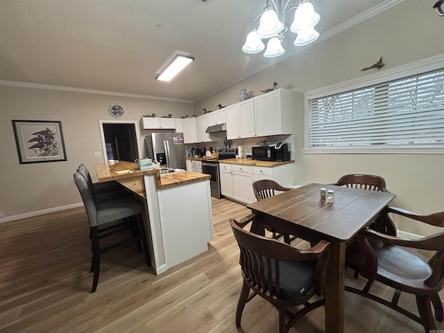 kitchen with pendant lighting, appliances with stainless steel finishes, wood counters, white cabinetry, and an inviting chandelier