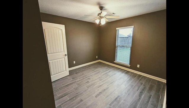 empty room featuring ceiling fan, dark hardwood / wood-style floors, and a textured ceiling