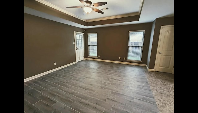 unfurnished room with a raised ceiling, ceiling fan, dark hardwood / wood-style flooring, and ornamental molding