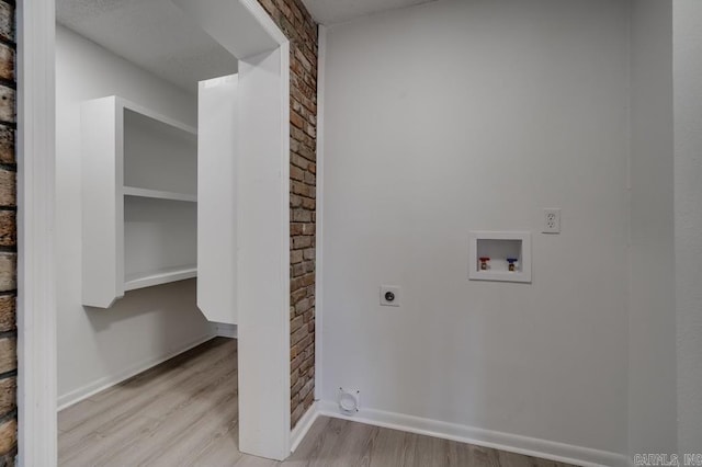 washroom featuring washer hookup, brick wall, hookup for an electric dryer, and light wood-type flooring