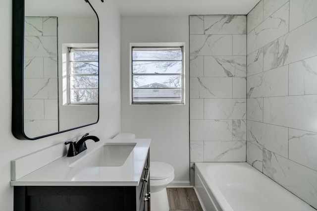 full bathroom with wood-type flooring, toilet, vanity, and tiled shower / bath combo