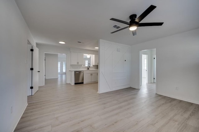 unfurnished living room featuring light wood-type flooring, ceiling fan, and sink