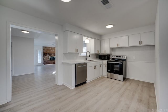 kitchen featuring white cabinets, stainless steel appliances, tasteful backsplash, light hardwood / wood-style floors, and sink