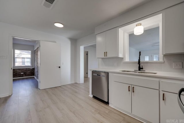 kitchen featuring decorative backsplash, brick wall, dishwasher, white cabinets, and sink