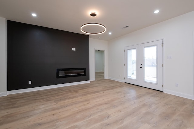 unfurnished living room featuring french doors and light hardwood / wood-style flooring