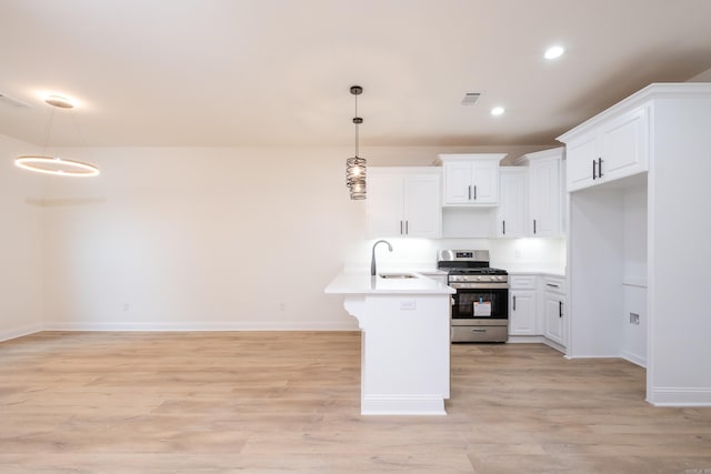 kitchen with white cabinetry, pendant lighting, light wood-type flooring, and stainless steel gas range oven