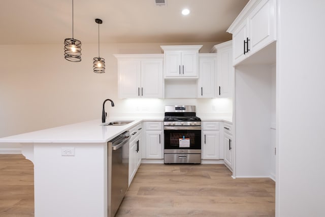 kitchen featuring light hardwood / wood-style floors, sink, white cabinetry, hanging light fixtures, and appliances with stainless steel finishes