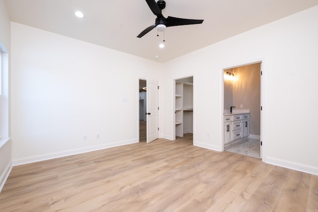 unfurnished bedroom featuring a spacious closet, ensuite bathroom, light hardwood / wood-style floors, ceiling fan, and a closet