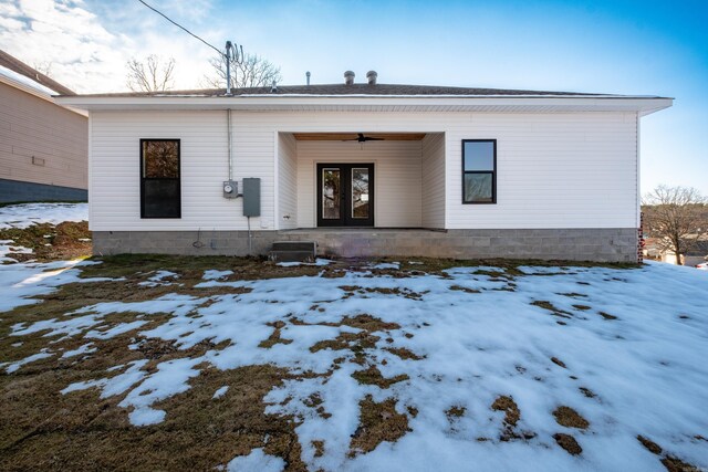 snow covered property entrance with ceiling fan and french doors