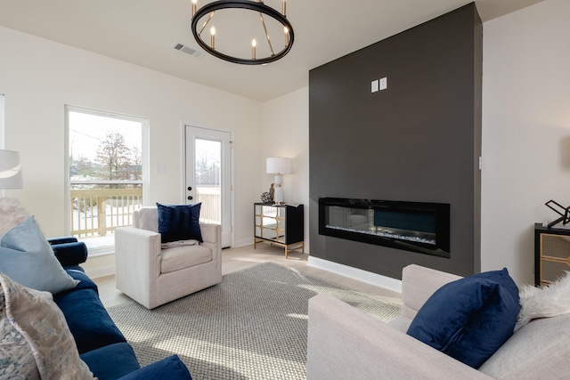 living room featuring a large fireplace, a wealth of natural light, and a notable chandelier