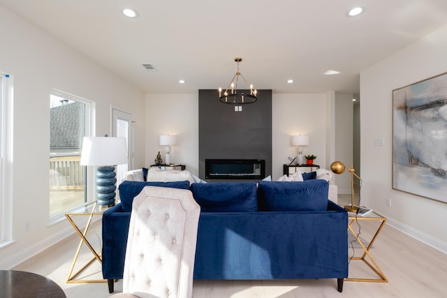 living room featuring a large fireplace, a notable chandelier, and light wood-type flooring