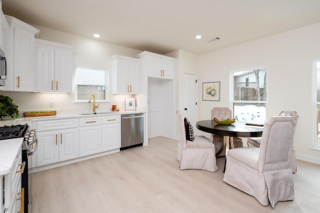 kitchen with light hardwood / wood-style floors, sink, stainless steel appliances, and white cabinetry