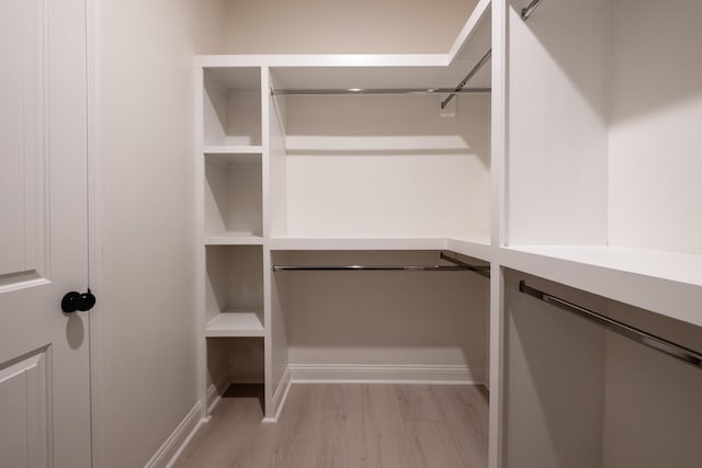 walk in closet with light hardwood / wood-style floors