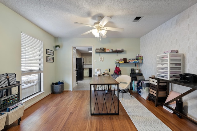 home office featuring ceiling fan, wood-type flooring, and a textured ceiling