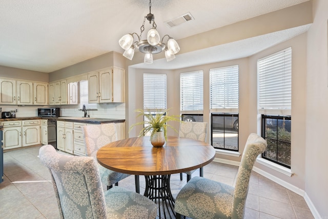 dining area featuring a textured ceiling, light tile patterned floors, and an inviting chandelier