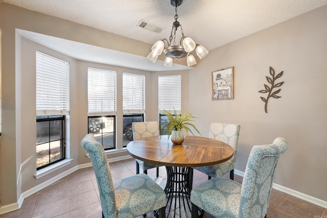 tiled dining area with a chandelier and a textured ceiling