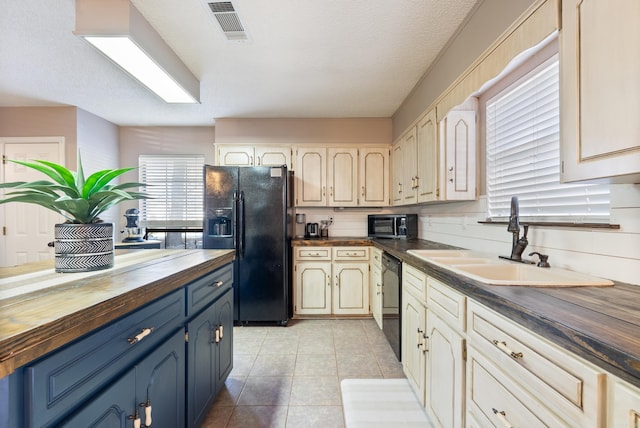 kitchen featuring a textured ceiling, black appliances, wooden counters, sink, and light tile patterned flooring