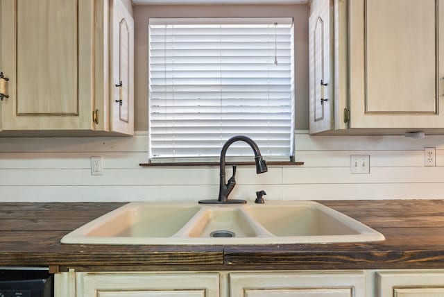 details featuring light brown cabinetry, sink, and wood walls