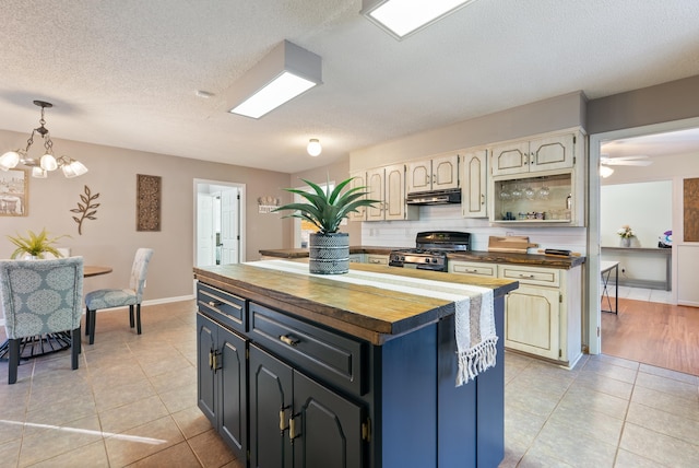 kitchen with a textured ceiling, stainless steel range oven, a kitchen island, wood counters, and cream cabinets