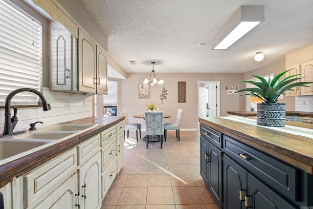 kitchen featuring cream cabinets, butcher block countertops, and decorative light fixtures