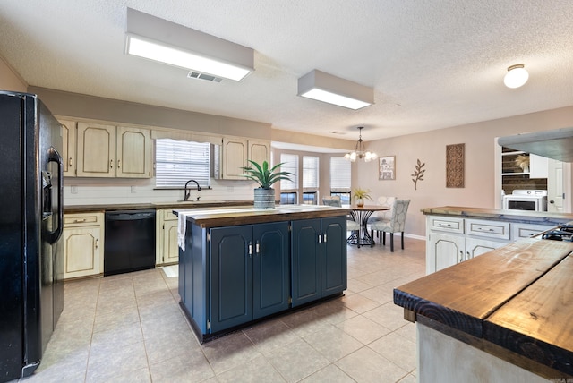 kitchen featuring an inviting chandelier, a textured ceiling, a kitchen island, pendant lighting, and black appliances