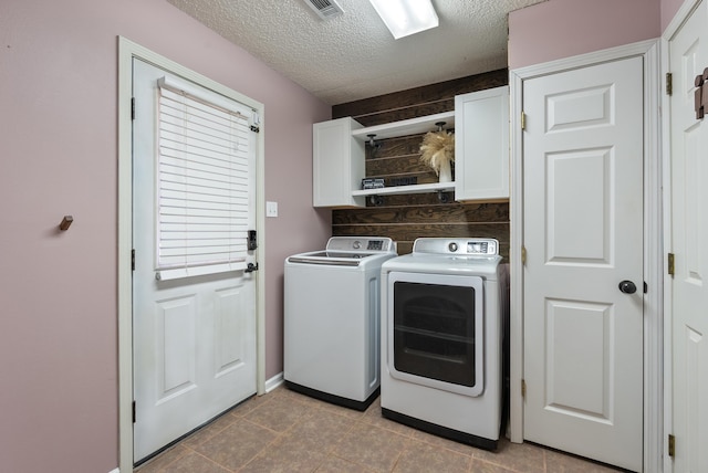 laundry area featuring a textured ceiling, cabinets, and separate washer and dryer